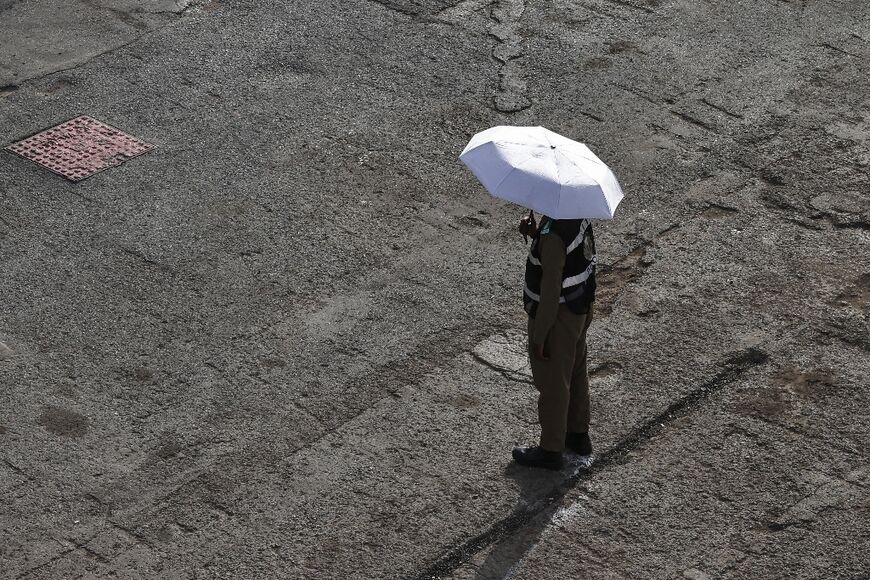 A member of the security forces shelters from the sun under an umbrella in Mina near Mecca