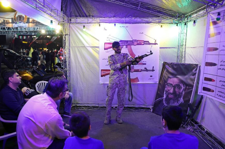 Iranian military personnel educate people about how to use a gun at a booth in Tehran 