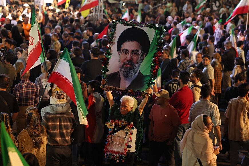 A man holds a portrait of Iran's supreme leader Ayatollah Mojtaba Khamenei while attending the farewell ceremony in Tehran of Iran's national football team for the World Cup