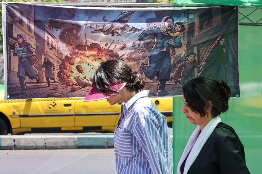 People walk past a banner depicting US-Israeli military attacks on Iran in the capital Tehran