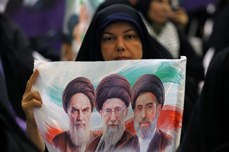 An Iranian woman holds an image of former and the current Iranian supreme leaders in Tehran