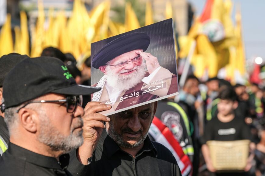 A mourner holds a portrait of Iran's slain supreme leader Ali Khamenei as people gather for a funeral procession in Iraq