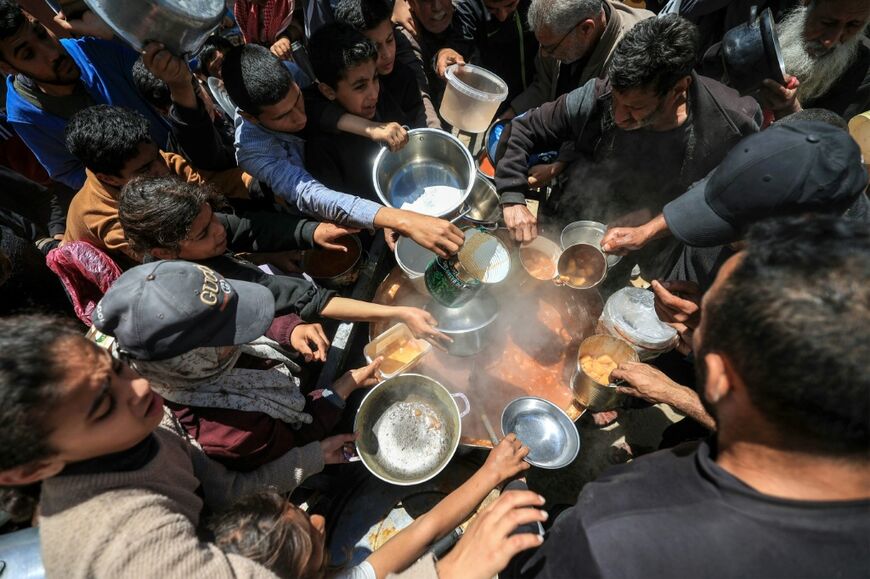 Displaced Palestinians receive food from a charity kitchen at a refugee camp in the central Gaza Strip in April 2026