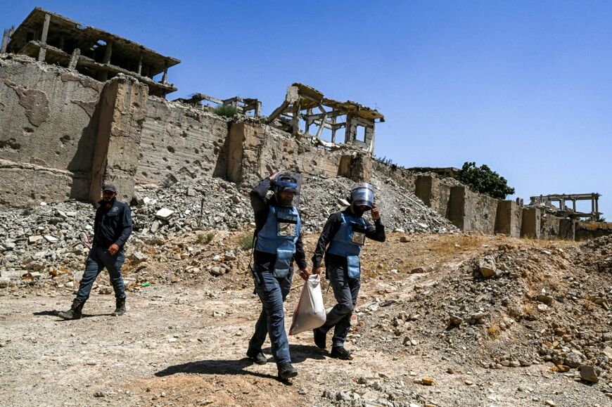 Members of a humanitarian NGO work to clear landmines and other explosive devices prepare to detonate unexploded war-remnants in a suburb of Damascus, Syria