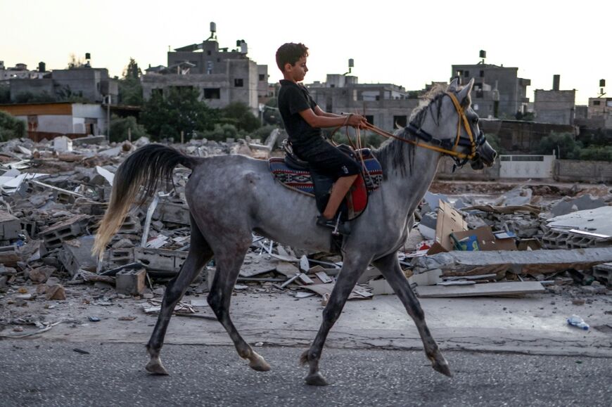A Palestinian boy rides a horse past the rubble of nearly two dozen shops that were demolished by Israeli bulldozers, citing the lack of a building permit
