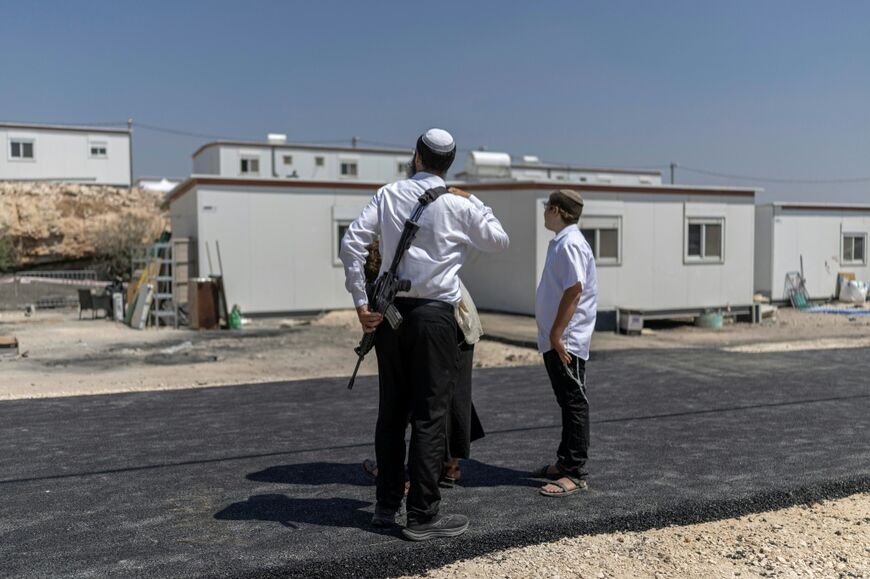 Israeli settlers stand outside houses after the reopening of a formerly abandoned settlement at Ganim