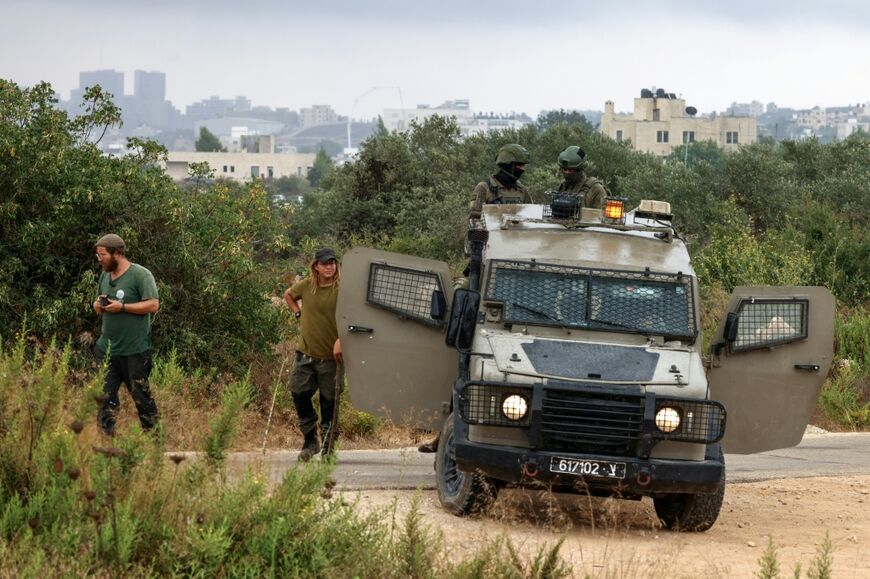 An Israeli army jeep is stationed alongside Israeli settlers near the area where Israeli bulldozers demolish Palestinian-owned buildings, citing the lack of building permits, on the outskirts of Birzeit, north of Ramallah, in the occupied West Bank on August 31, 2026