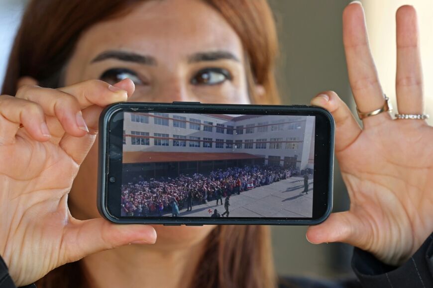Principal May Mehdi shows a photograph of Burj Qalaway Intermediate School before it was damaged by Israeli strikes