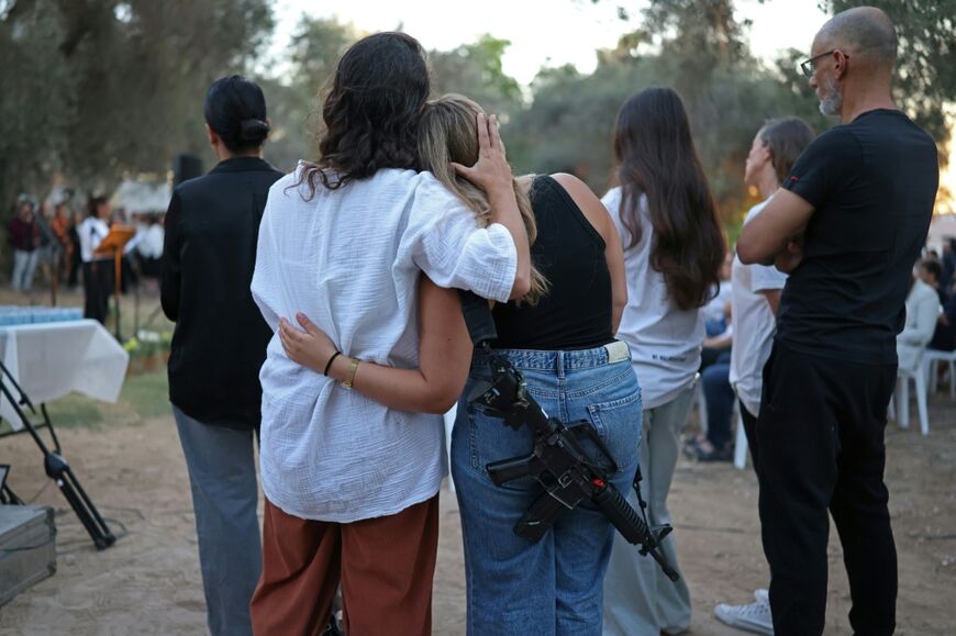 Israelis embrace one another while attending an October 7 attack three-year-anniversary tribute ceremony at the Kibbutz Kfar Aza