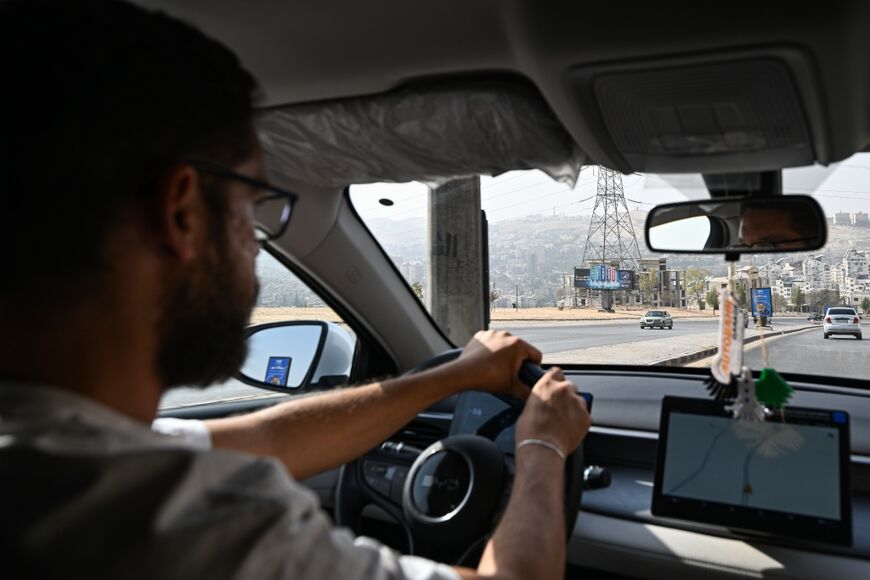 Ahmed Al-Lahham, a driver for ride-hailing application "Yalla Go!", drives his plug-in hybrid vehicle (PHEV) in Damascus