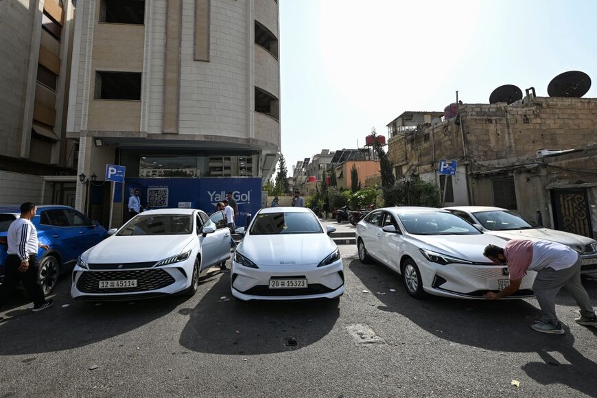 Plug-in hybrid vehicles (PHEV) operating under ride-hailing application "Yalla Go!" are seen parked on a street in Damascus