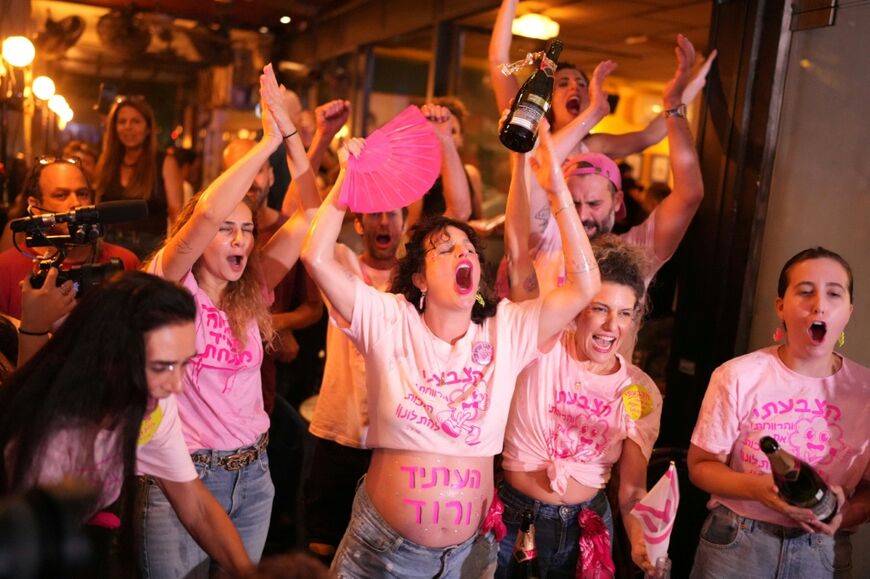 Israelis cheer at a bar after the first exit polls were announced, in Tel Aviv