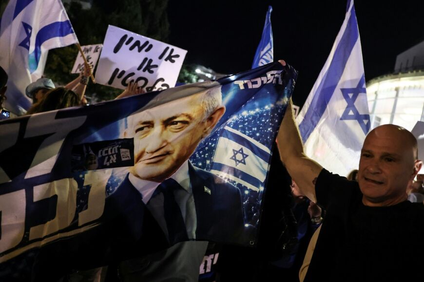 A right-wing protester holds a banner in support of Israeli Prime Minister Benjamin Netanyahu in a counter-demonstration in Tel Aviv