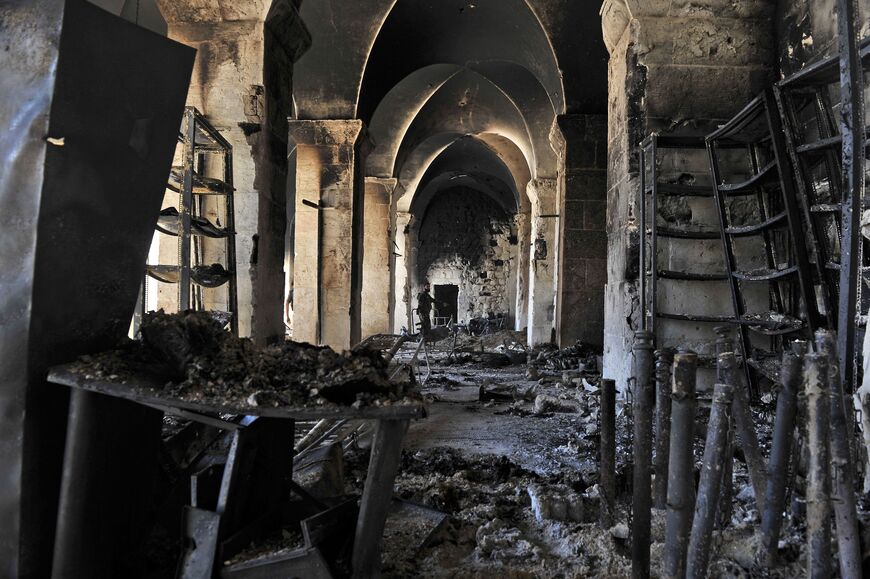 A Syrian rebel (rear) walks inside a burnt section of the Umayyad Mosque in the old city of Aleppo hours before the Syrian army retook control of the complex on October 14, 2012. Syria's army retook control of the historic mosque after fierce clashes with rebels in and around the area, a military official and the Syrian Observatory for Human Rights said. AFP PHOTO/Tauseef MUSTAFA (Photo by TAUSEEF MUSTAFA / AFP) (Photo by TAUSEEF MUSTAFA/AFP via Getty Images)