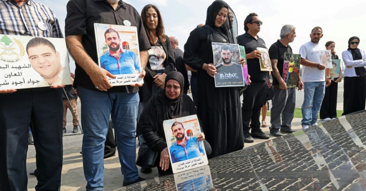 Family members carry the portraits of the victims of 2020 Beirut port blast as they gather around the marble memorial engraved with the names of the victims near the blast's ground zero
