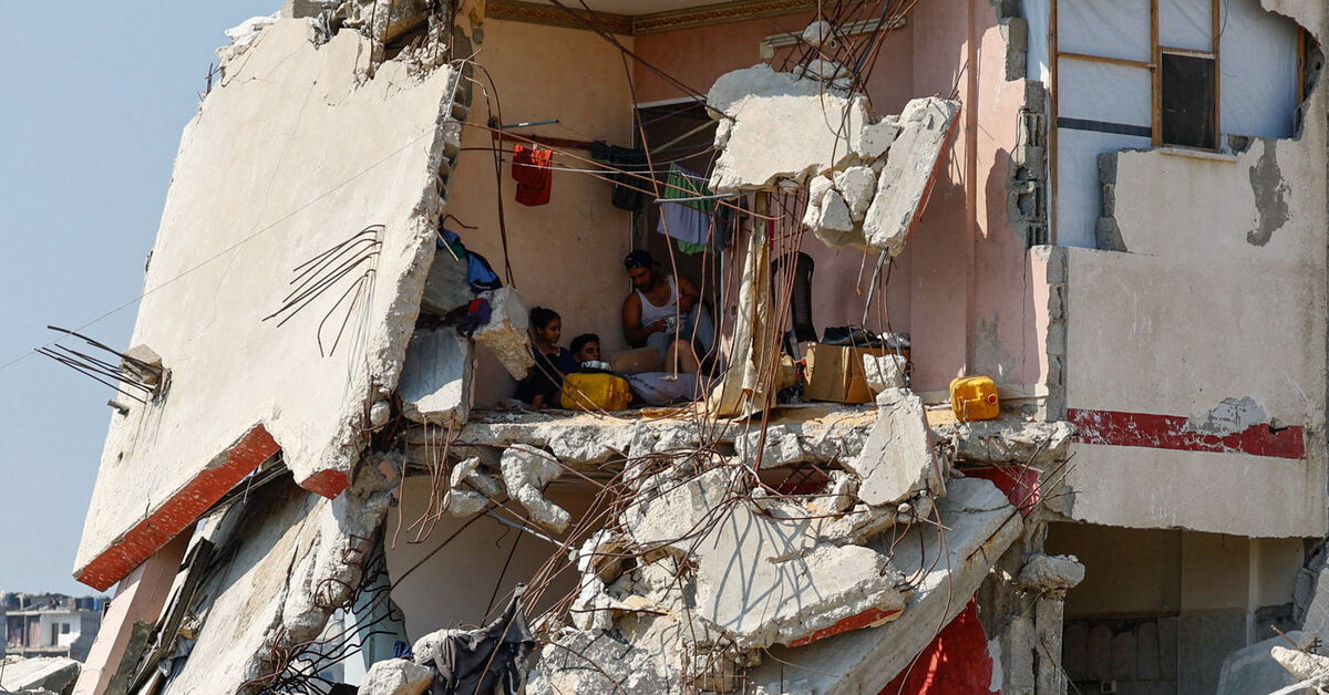 Palestinians sit inside a house damaged during the war, surrounded by destroyed buildings, in Gaza City, August 15, 2026. REUTERS/Mahmoud Issa