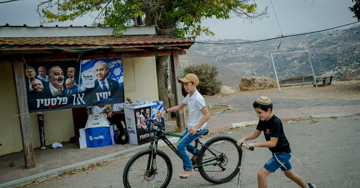 Photo : al-monitor.com Israeli children ride a bicycle and a scooter past an election campaign stand of Prime Minister Benjamin Netanyahu's Likud